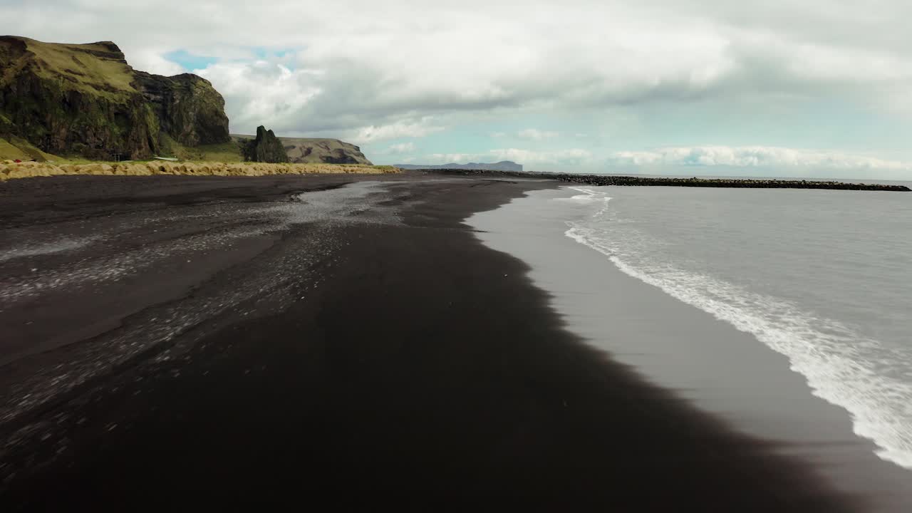 앞으로 나아가는 아이슬란드의 검은 모래 해변의 공중 샷