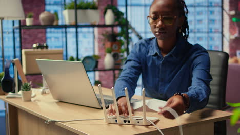 african american woman restarting her wireless router and checking network