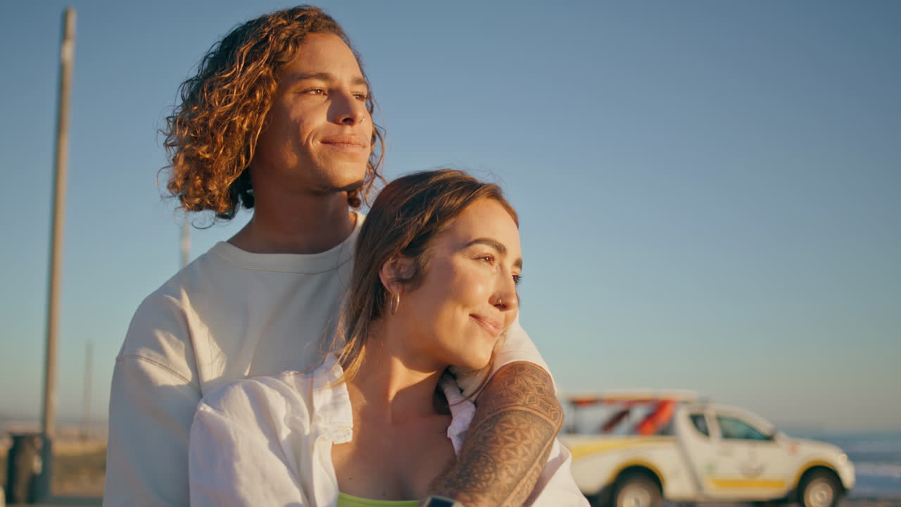 una pareja se abraza en la playa al atardecer.