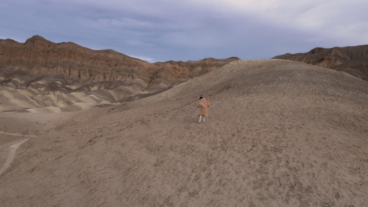 A solitary figure in a vast desert mountain landscape