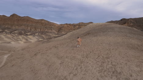 a solitary figure in a vast desert mountain landscape