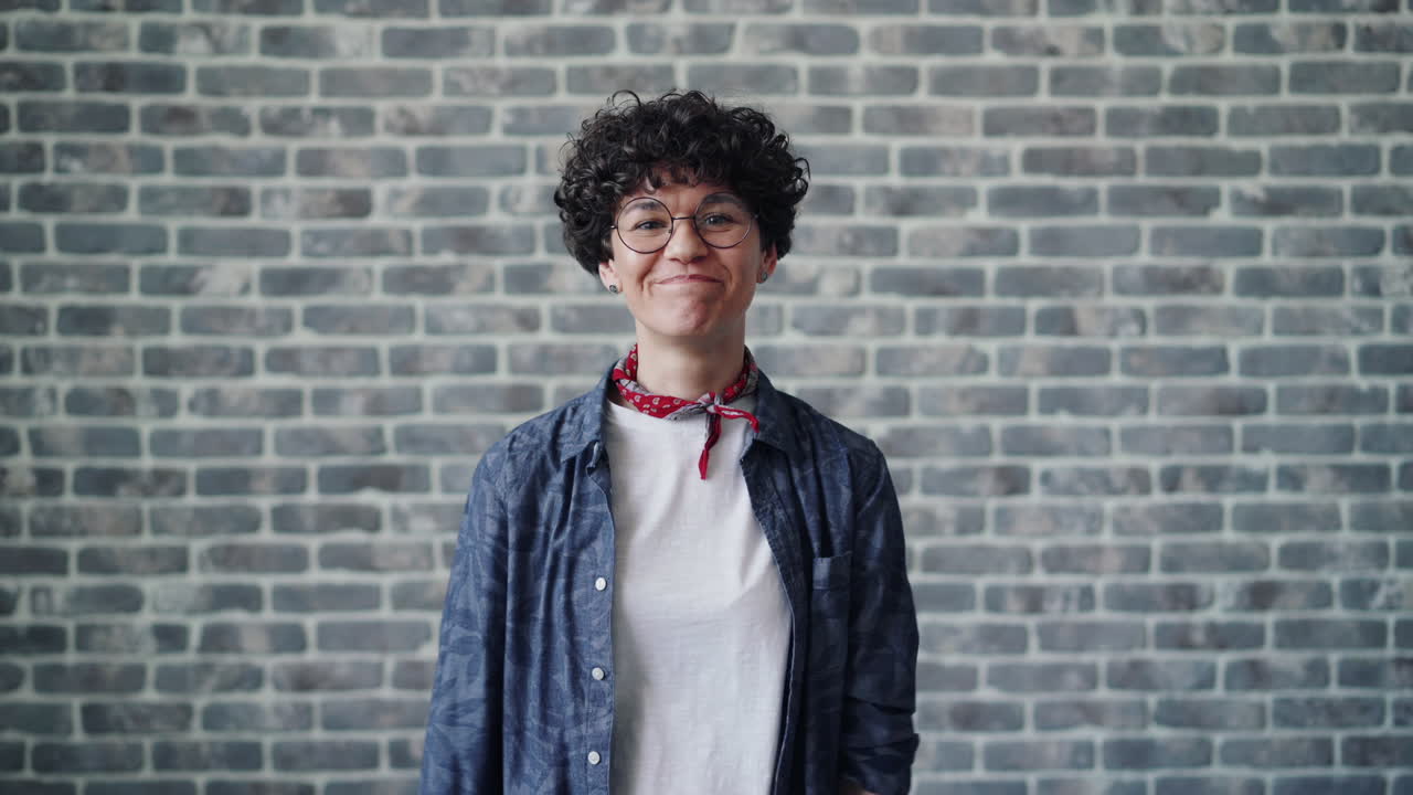 Woman with expressive face in front of brick wall