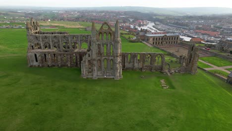 ruinas históricas de la abadía de whitby con ciudad costera en el fondo en el norte de yorkshire, inglaterra, reino unido
