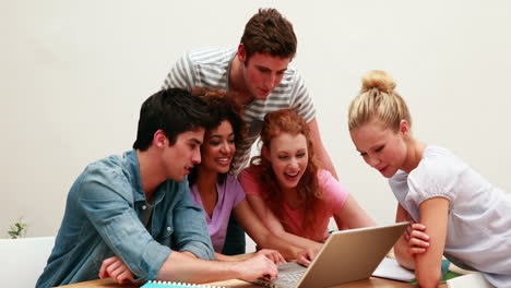 estudiantes alegres usando la computadora portátil juntos