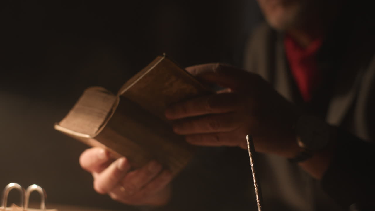 Vieil homme passionné lit un livre dans son bureau la nuit