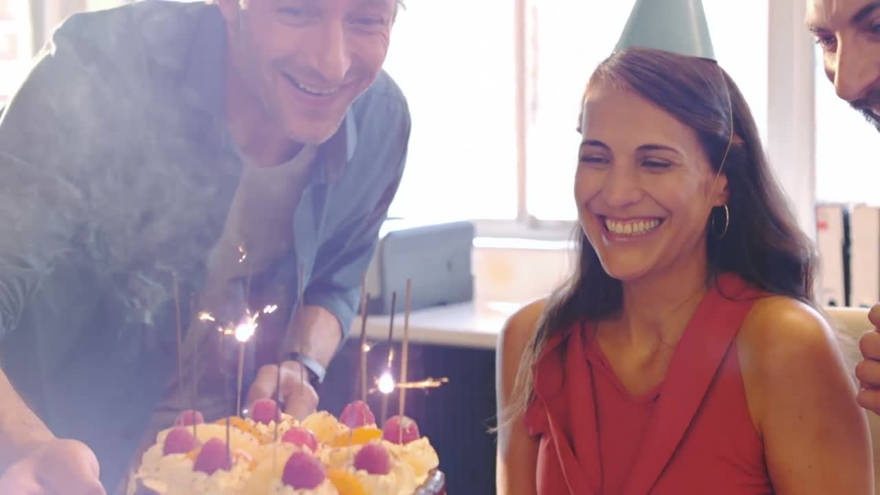 colegas celebrando el cumpleaños de una mujer ejecutiva de negocios
