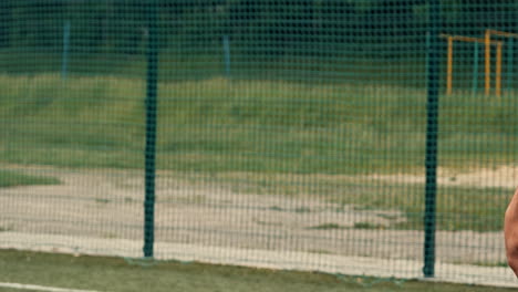 close-up de um jogador de futebol irreconhecível em pé e segurando uma bola de futebol em um campo de futebol de rua