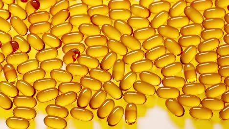 yellow translucent gel capsules with omega 3, vitamin d, fish oil or cod liver oil falling on white reflective surface. pile of vitamin pills supplement. healthy diet concept