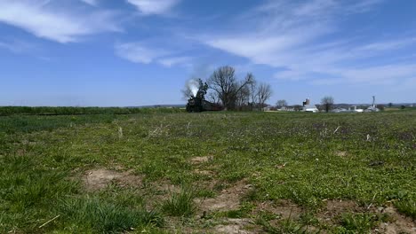 Tren-De-Vapor-Resoplando-A-Lo-Largo-De-Las-Tierras-De-Cultivo-Amish-Visto-Por-Un-Dron