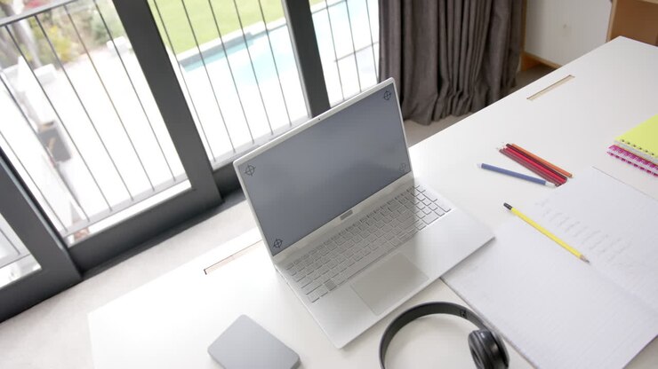 Close up of laptop with copy space on screen and headphones on desk, slow motion