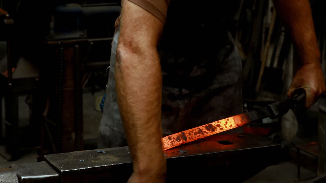 herrero martillando una barra de metal caliente 4k