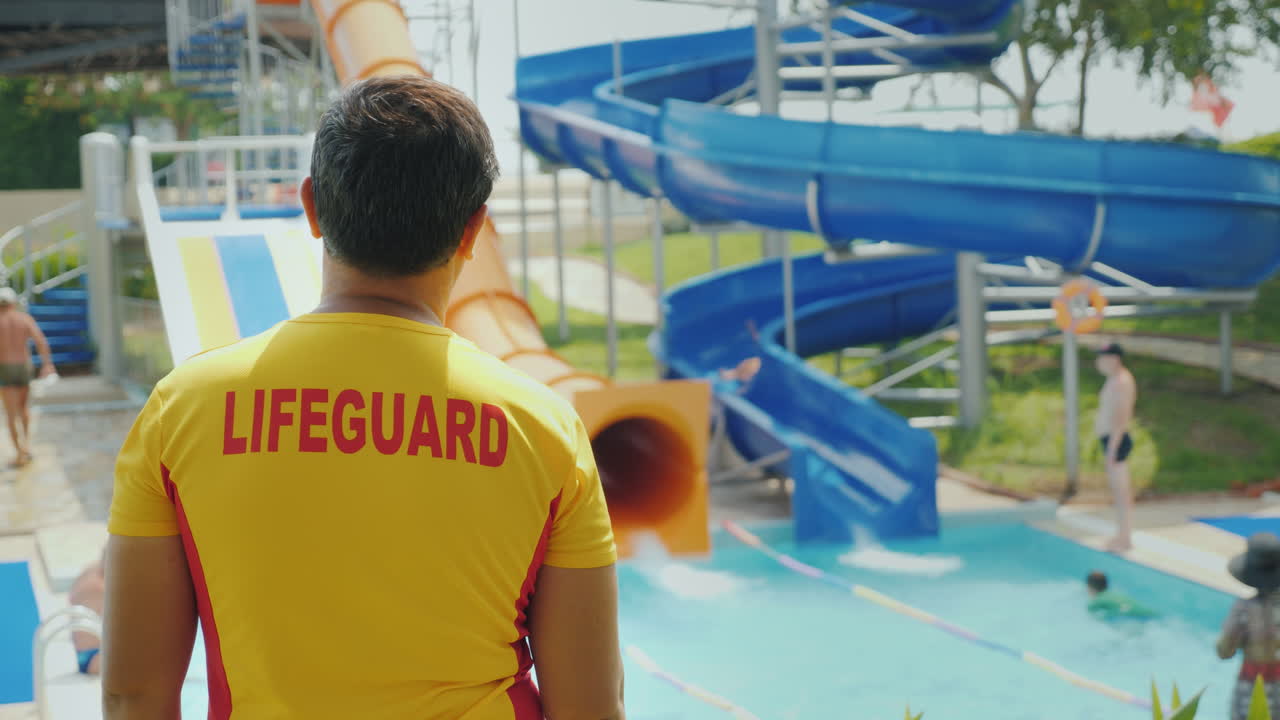 남자 인명 구조 원이 워터 슬라이드 근처에서 근무 중입니다.