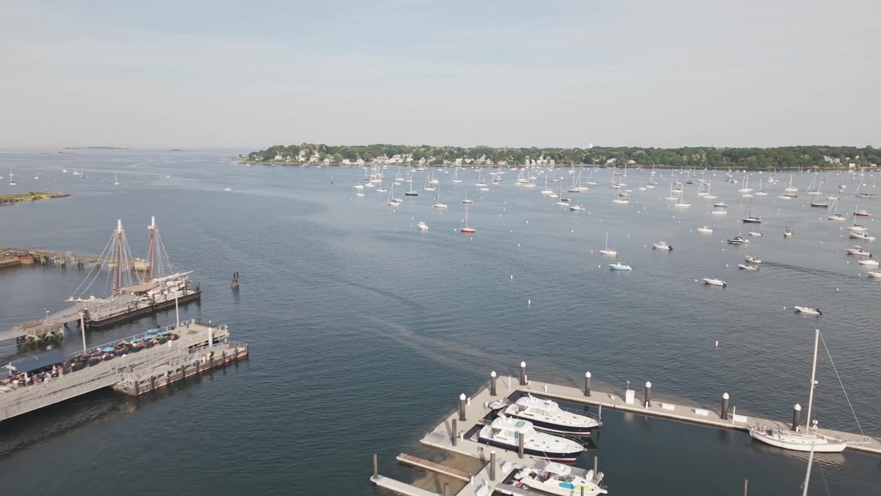 Tomas aéreas de barcos y yates en el puerto de Salem, Massachusetts, en un cálido día de verano. Vistas al océano con toma panorámica.