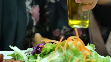 pouring olive oil on a fresh salad