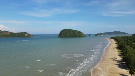 a descending aerial footage of islands, beachfront, blue sky, and jet skis making circles on the water