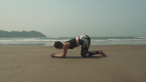 kneeling yoga practice on spectacular black sand beach with waves in background