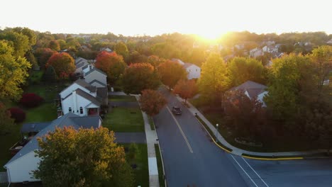 pick up truck turns onto street through residential neighborhood community, colorful autumn fall leaves line the road, evening glow or warm sunset