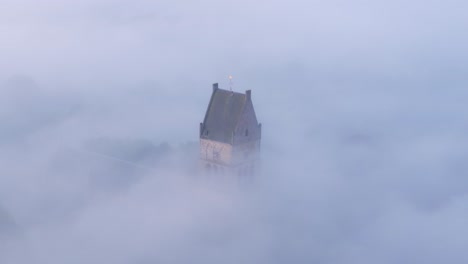 wide shot of the martinikerk bolsward towering above the fog, aerial