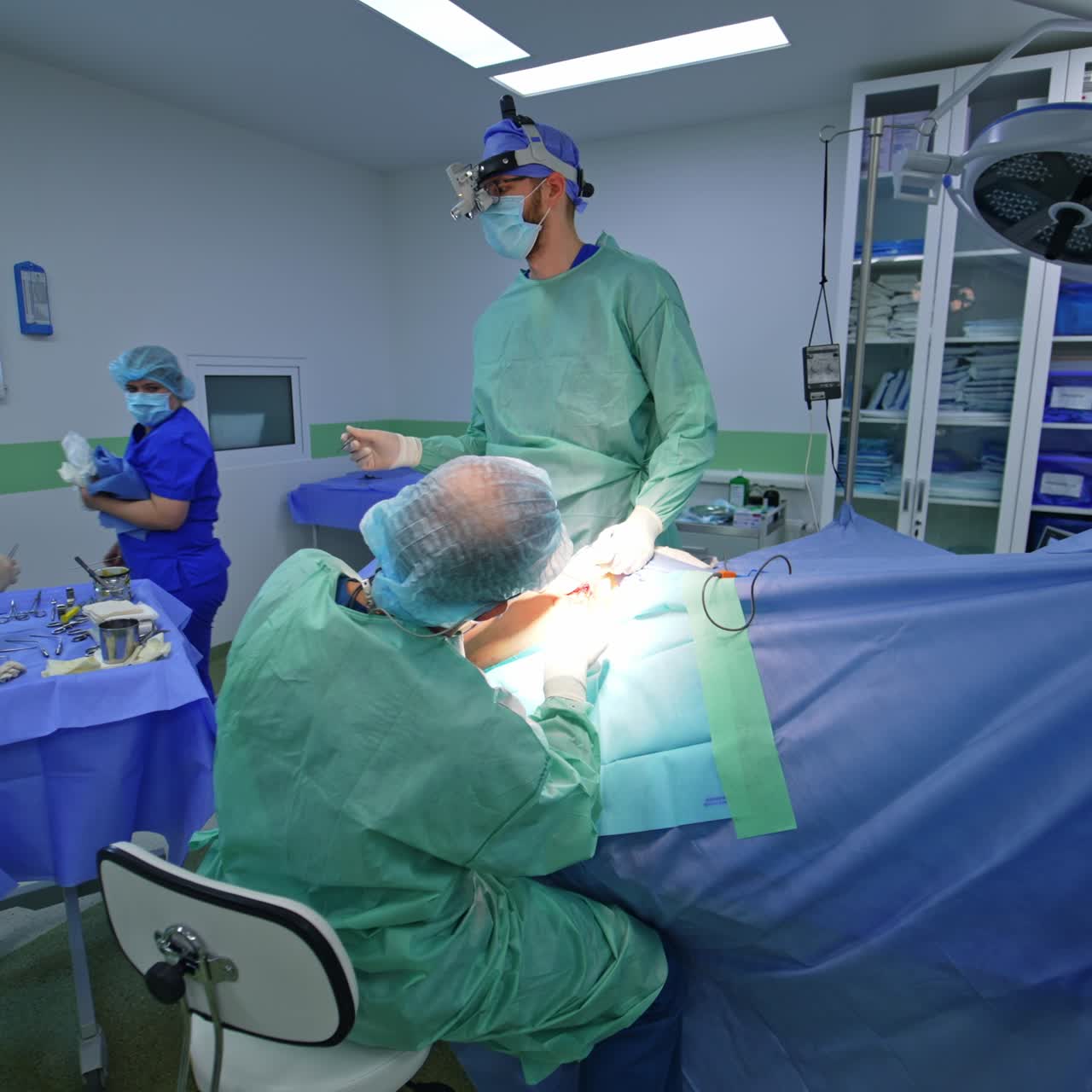 Approaching the surgical team conducting neurosurgical operation. Female nurse preparing instruments for surgeons