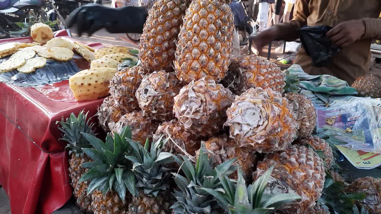 A shop owner sells pineapple to customers at a market on the first day of the holy fasting month of Ramadan in India