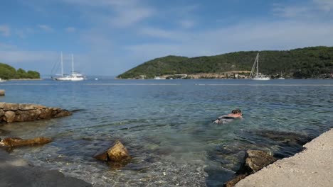 Man-snorkeling-in-coastal-seaside-town-by-mountains