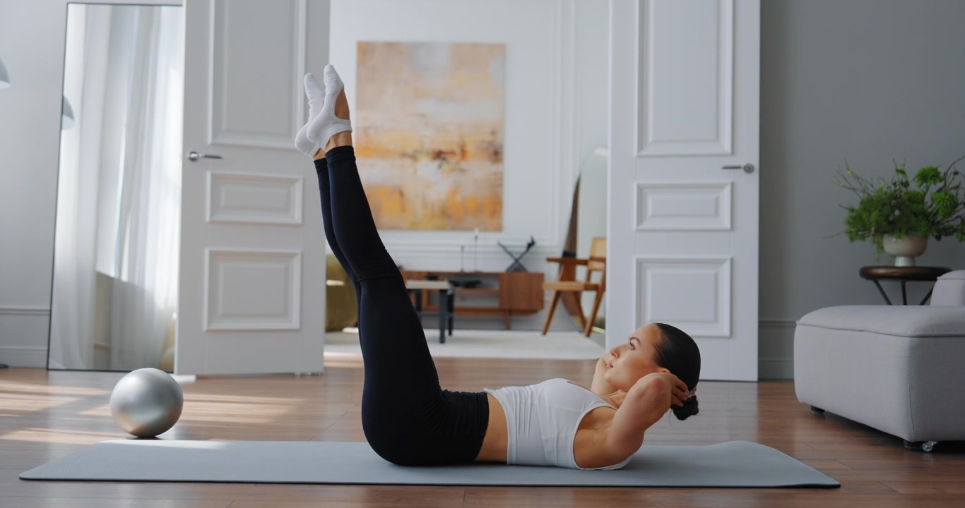 Young Woman Doing Leg Raises on Yoga Mat at Home