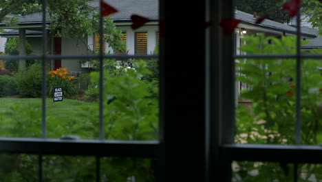 A-Black-Lives-Matter-sign-in-the-front-yard-as-seen-through-a-window-pane-with-a-heart-banner-from-the-house-across-the-street