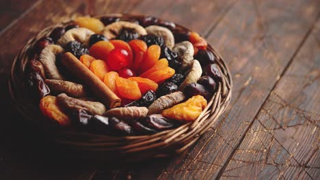 Mezcla-De-Frutas-Secas-En-Una-Pequeña-Cesta-De-Mimbre-Sobre-Mesa-De-Madera