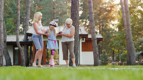 mom and grandmother are taught to roller-skate a girl of 6 years support her by the hand concept - t