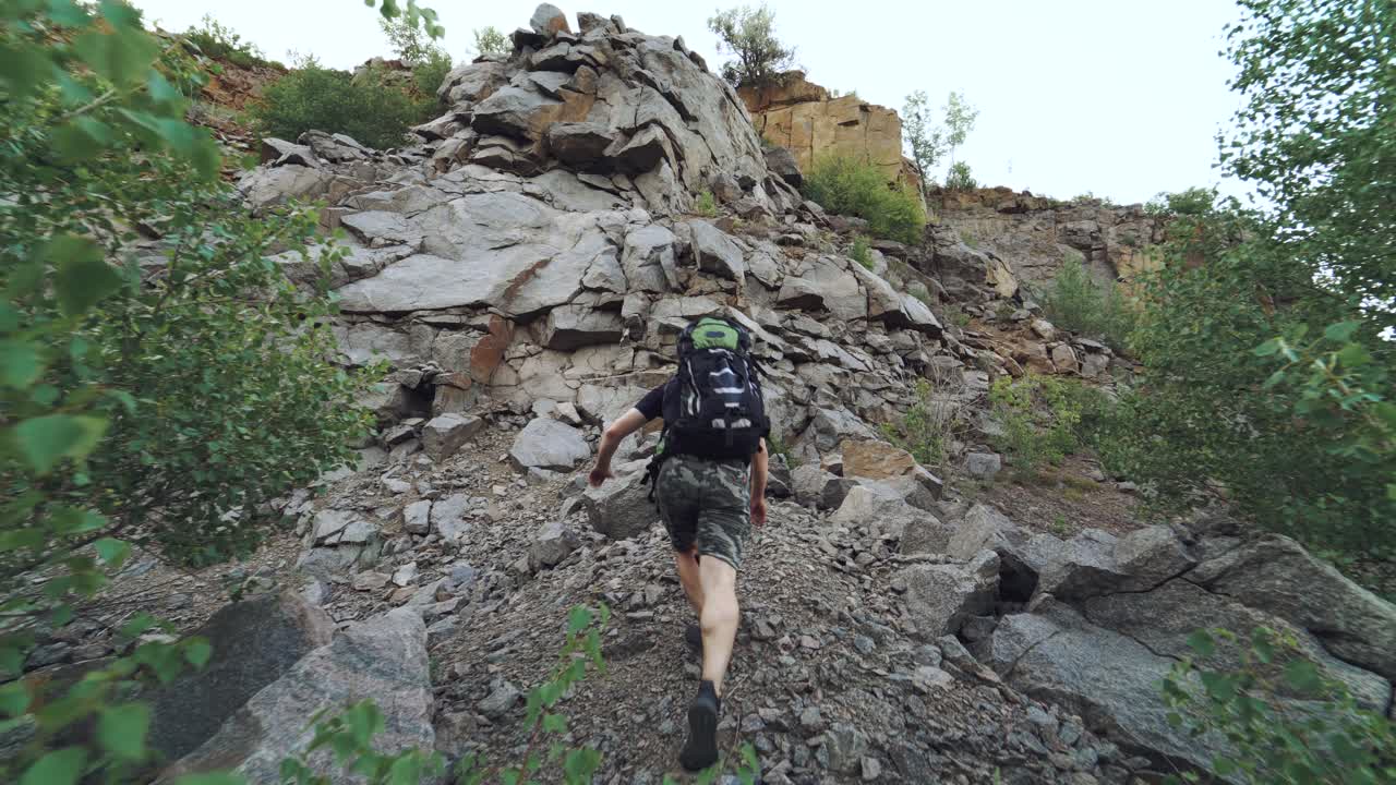 tourist with sports equipment is climbing a rock and viewing a beautiful place from height