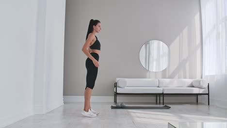 hermosa chica en forma haciendo ejercicio en casa realizando estiramientos laterales en una sala de estar