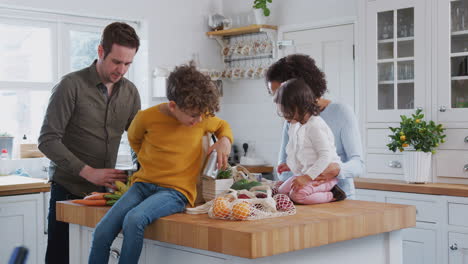 Familia-Regresando-A-Casa-Después-De-Un-Viaje-De-Compras-Usando-Bolsas-Sin-Plástico-Desempacando-Alimentos-En-La-Cocina