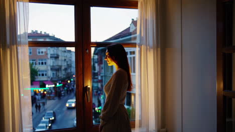 woman gazing at city view through window