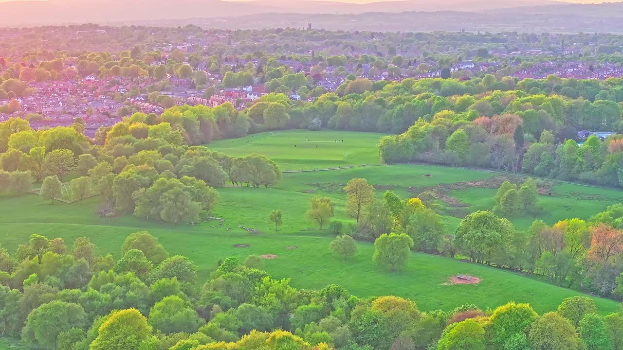 Aerial: Heaton Park with trees and forest at sunset in Prestwich, Manchester, England, crane up drone shot