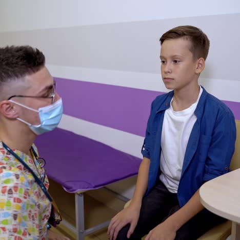 the doctor touches neck of the boy. checking tonsils at pediatrician. boy at kids clinic
