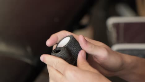 close up of tattoo artist hands preparing tattoo gun by ripping grip tape.