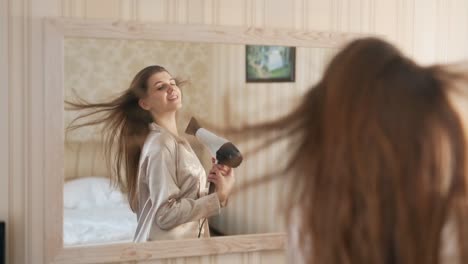 Una-Joven-Guapa-En-El-Espejo-Se-Seca-El-Pelo-Con-Un-Secador-De-Pelo