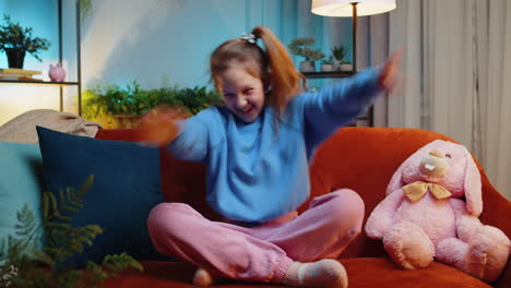feliz niño pequeño niña bailando y moviéndose al ritmo haciendo un gesto de baile dub de moda en el hogar moderno