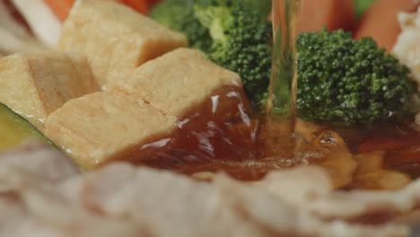 close up of pouring soup on shabu ingredients spinning around in the kitchen