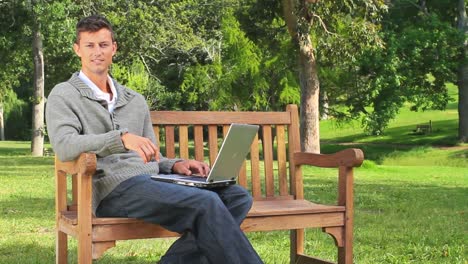 young man surfing on his laptop on a bench