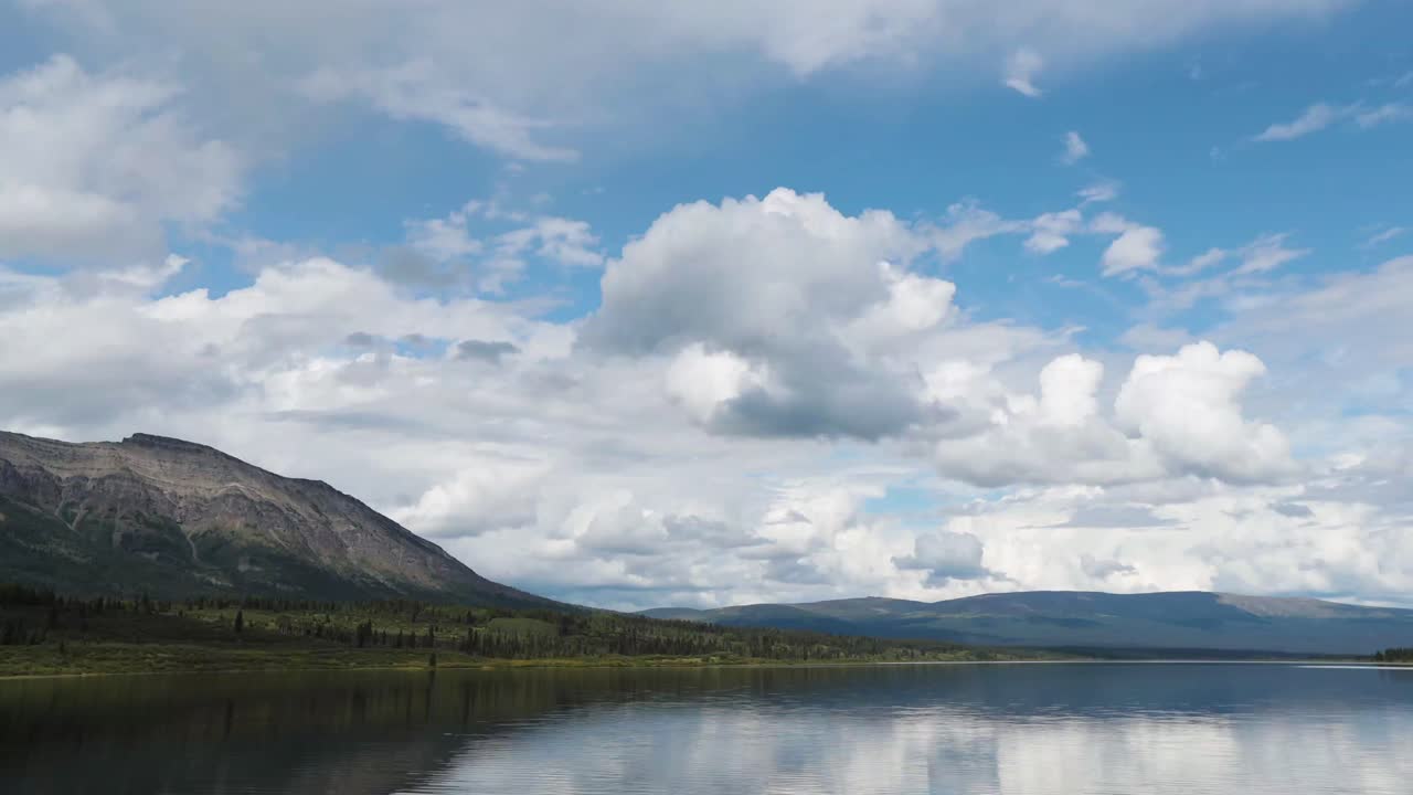 lapso de tiempo de un lago tranquilo con montañas en el fondo con nubes moviéndose rápidamente en la distancia