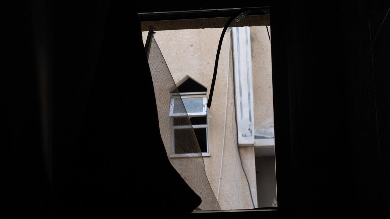 Vista di un edificio da dietro una finestra rotta nella città di Rafah, Palestina