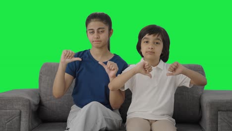 hermanos indios mostrando los pulgares hacia abajo a la pantalla verde de la cámara