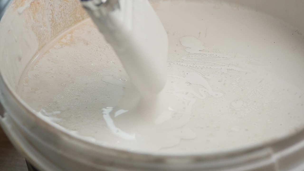 Painting with a brush in a paint bucket