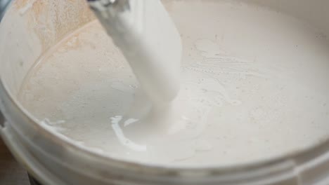 painting with a brush in a paint bucket