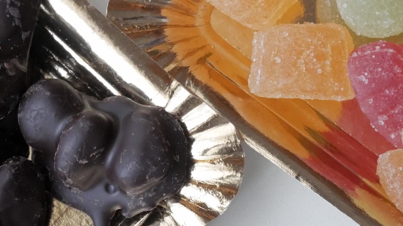 Panning right shot of multiple dark chocolate-covered almonds arranged on a golden tray