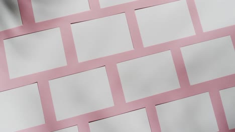 overhead view of white business cards arranged on pink background, copy space, slow motion