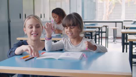 Happy-friendly-school-teacher-and-pupil-girl-at-desk