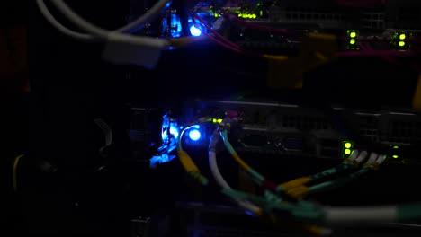 back data server connectors with fiber optic patch cables at cloud facility, close up rack focus shot