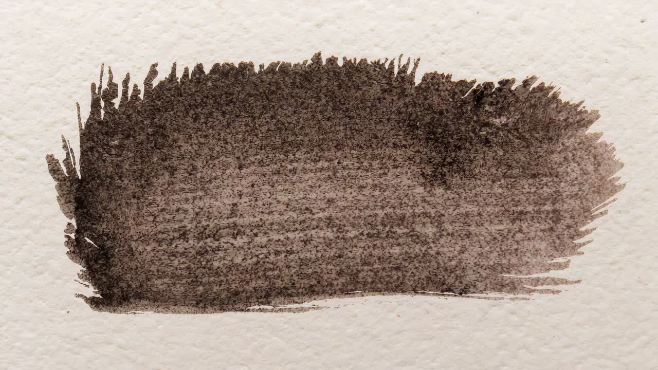 Drying horizontal brown brush stroke showing grain on cold-press watercolor paper after laying
